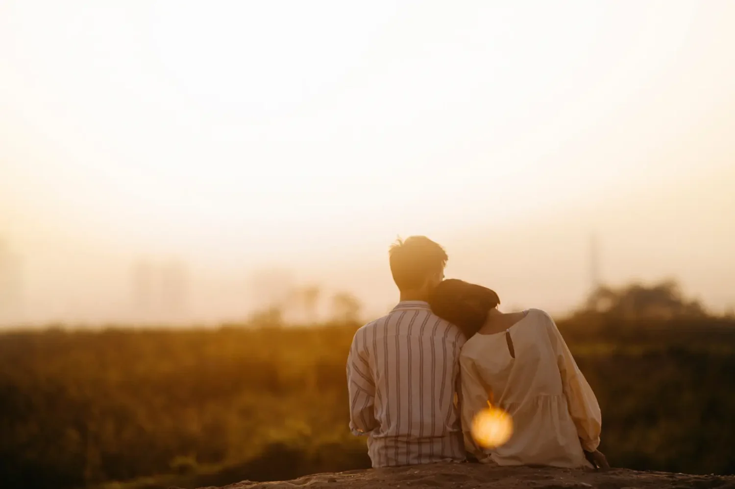 A couple sitting together outdoors at sunset.
