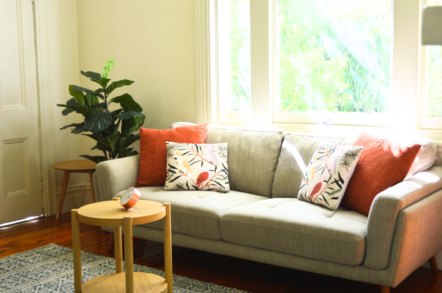 couch against a window with greenery seen on outside and colourful cushions on couch