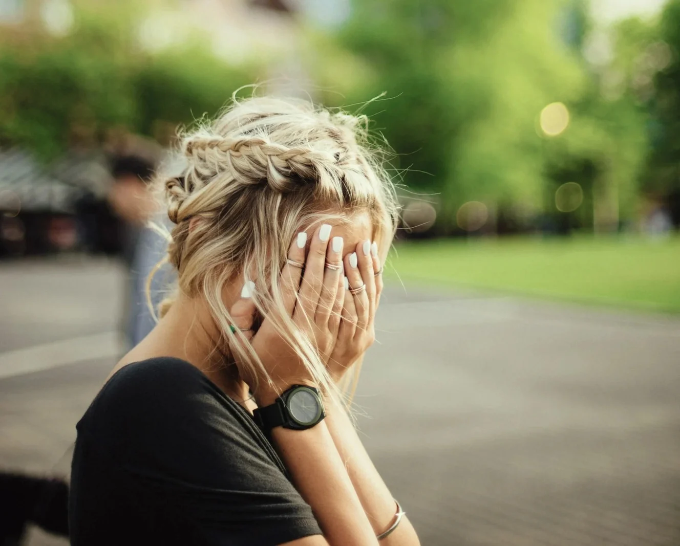 A woman covering her face with both hands outdoors.