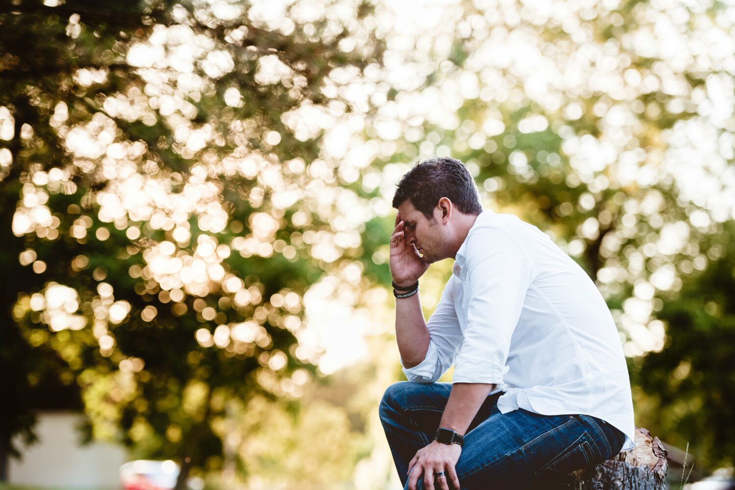 Man sitting on a bench in the park with head buried in hands