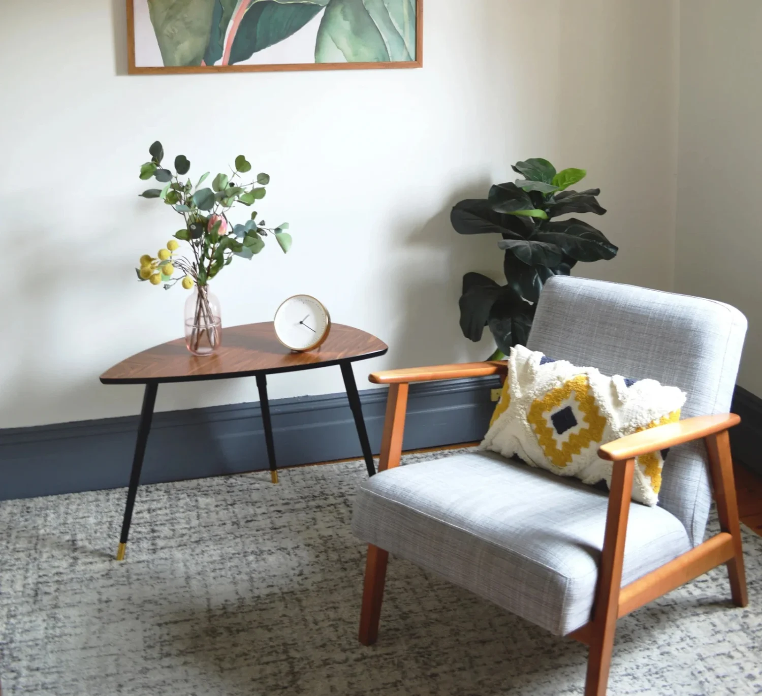 A chair beside a table with a vase of flowers and indoor plants.