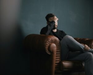 Man sitting on a couch with head in hand