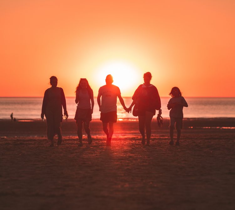 silhouette photo of five person walking on seashore during sunset