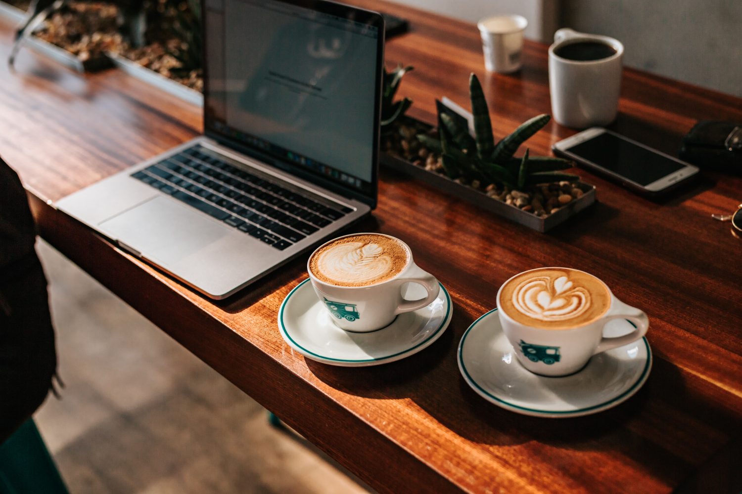 two coffees on wooden table with laptop