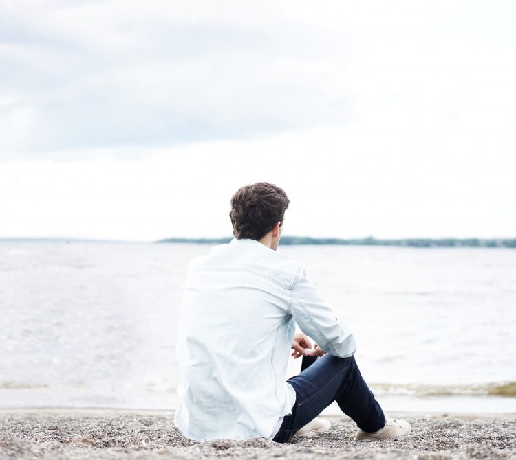 Back of male sitting on beach