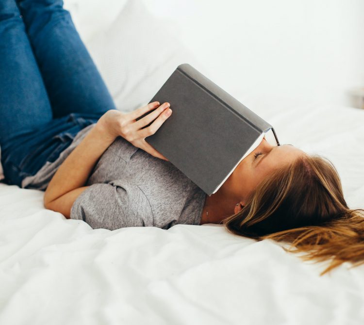 woman lying on bed holding book