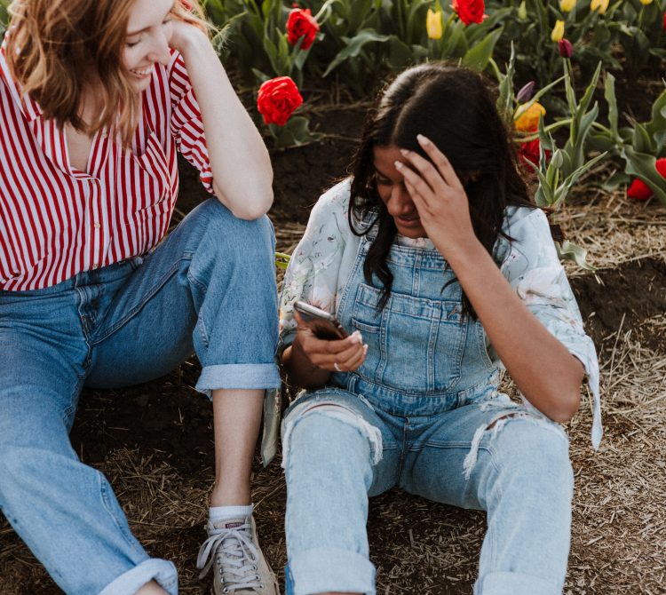 three young women chatting happily by flower field