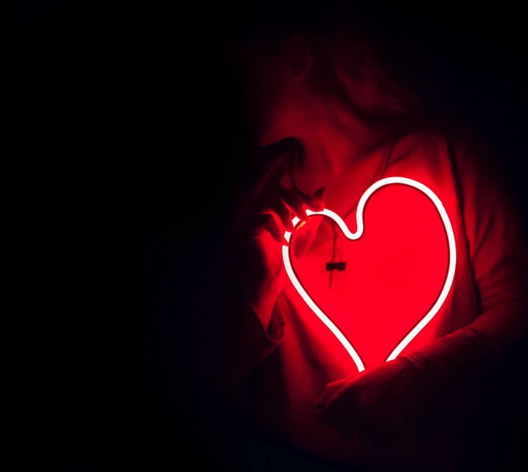 Women holding neon lighting heart on her chest