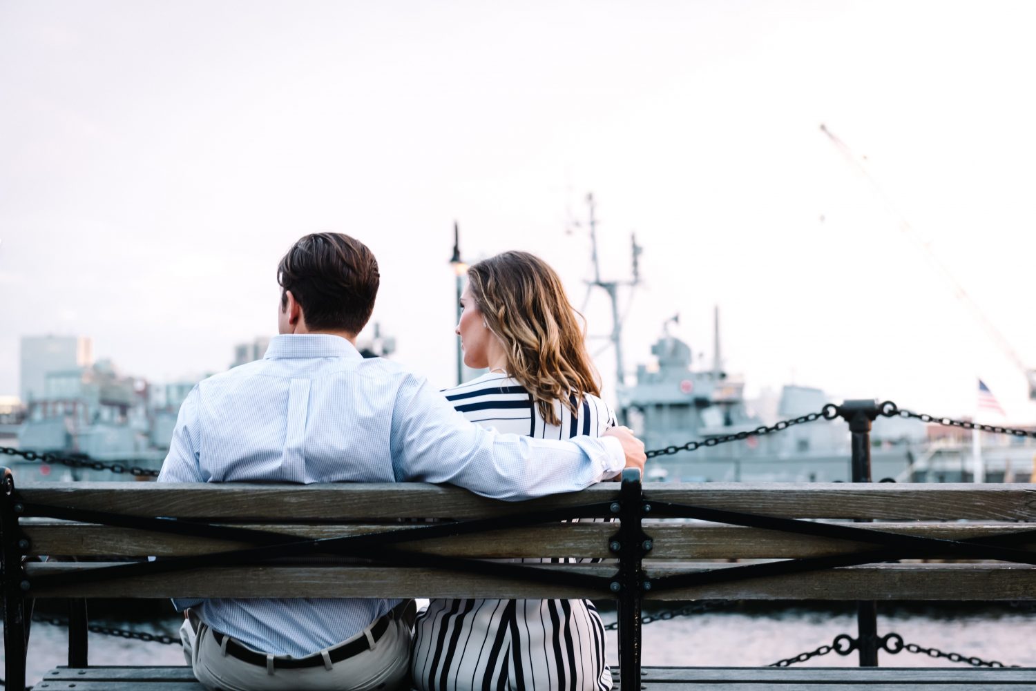 A man and a woman sitting on a bench looking out into the distance.