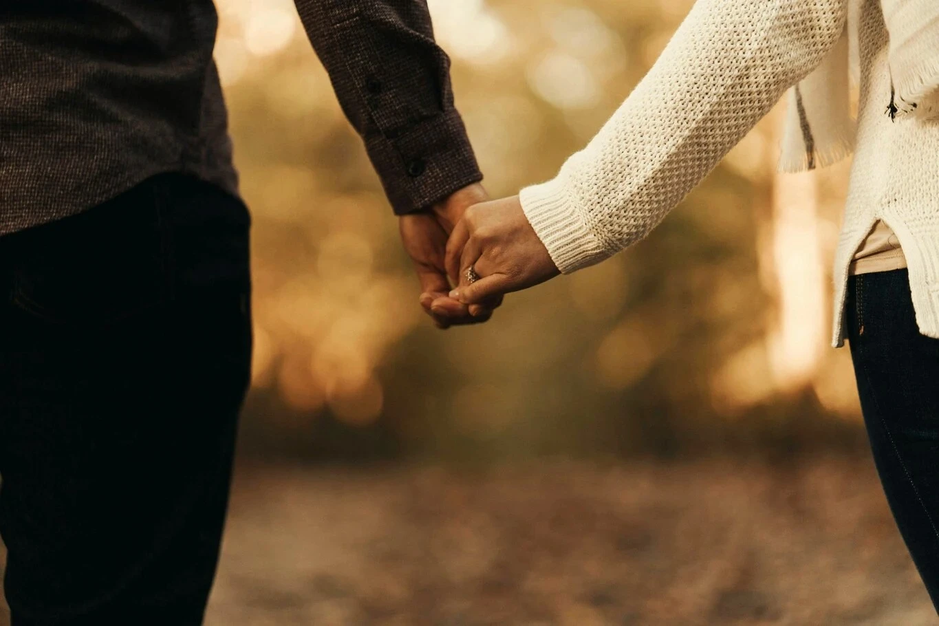 A couple holding hands while standing outdoors.