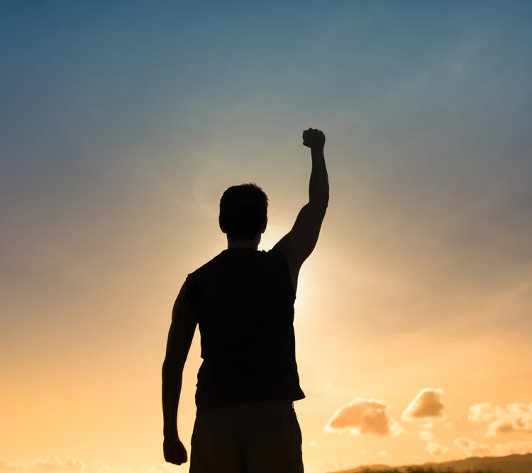 A silhouette of a man in the sunset with a fist in the air