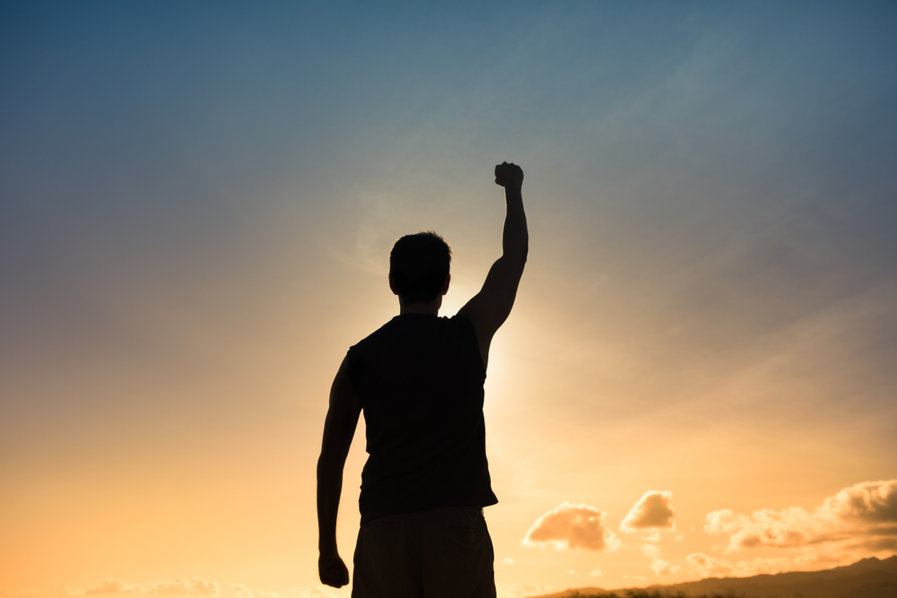 A silhouette of a man in the sunset with a fist in the air