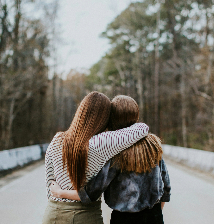 Two people standing on the road with their arms around each other.