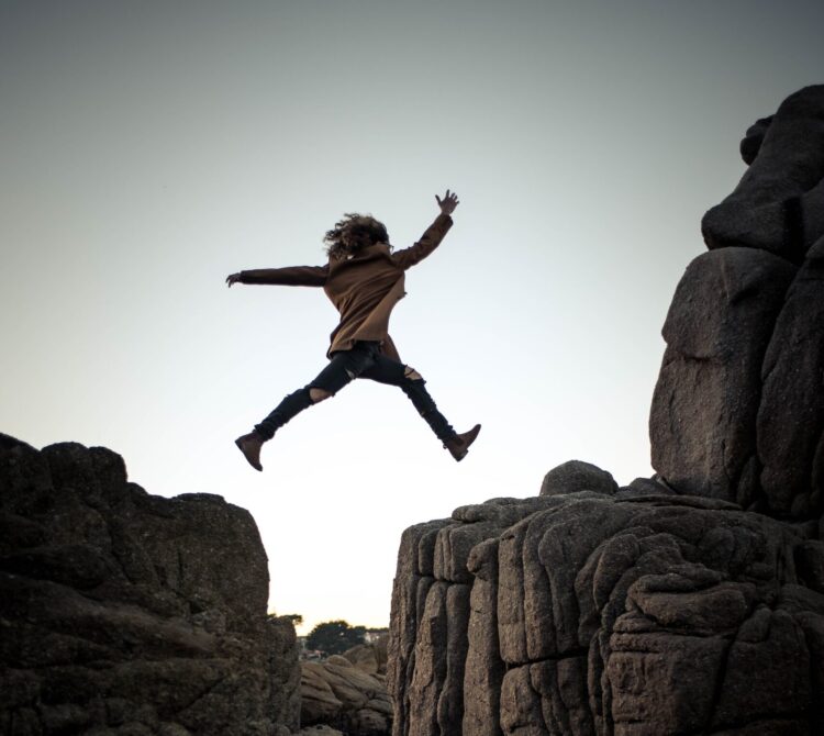 Person jumping between two rocks.