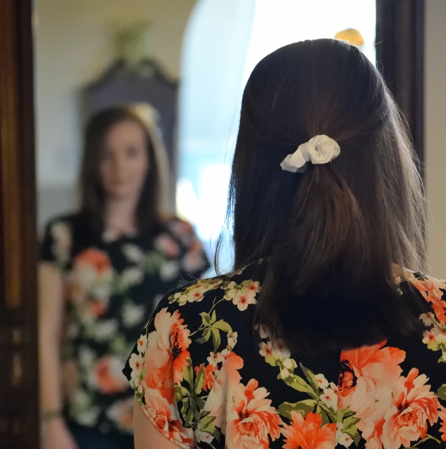 View of the back of a person head who is standing in front of mirror