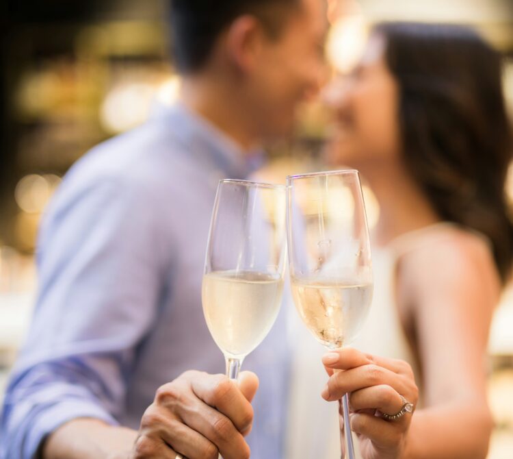Two people hold up champagne glasses at their engagement