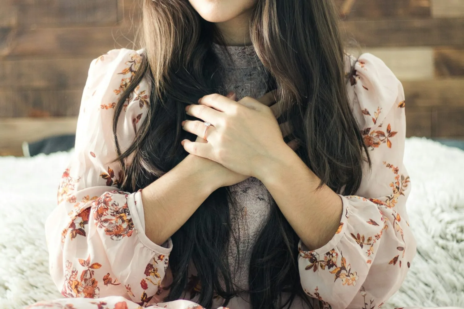 A woman with long brown hair, hands folded over her chest