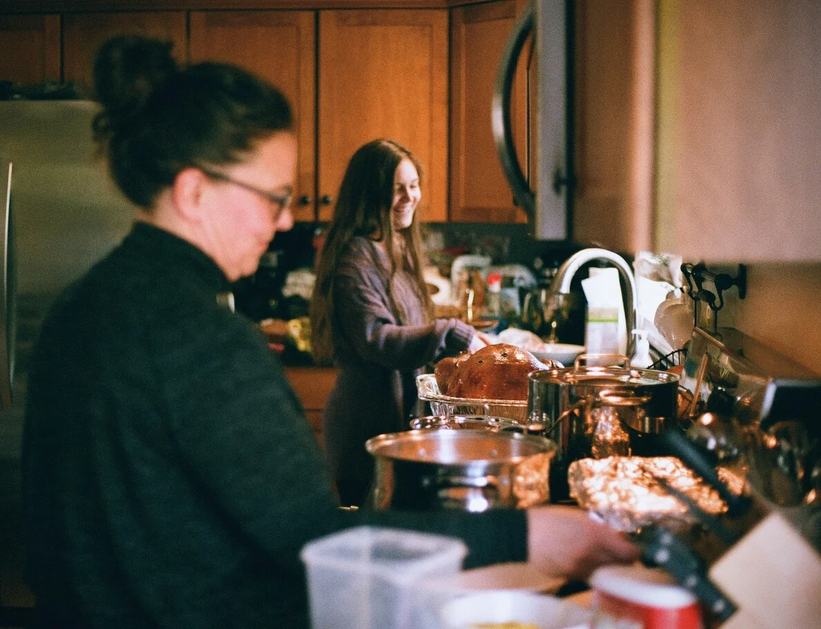Two girls preparing food together in a kitchen smiling