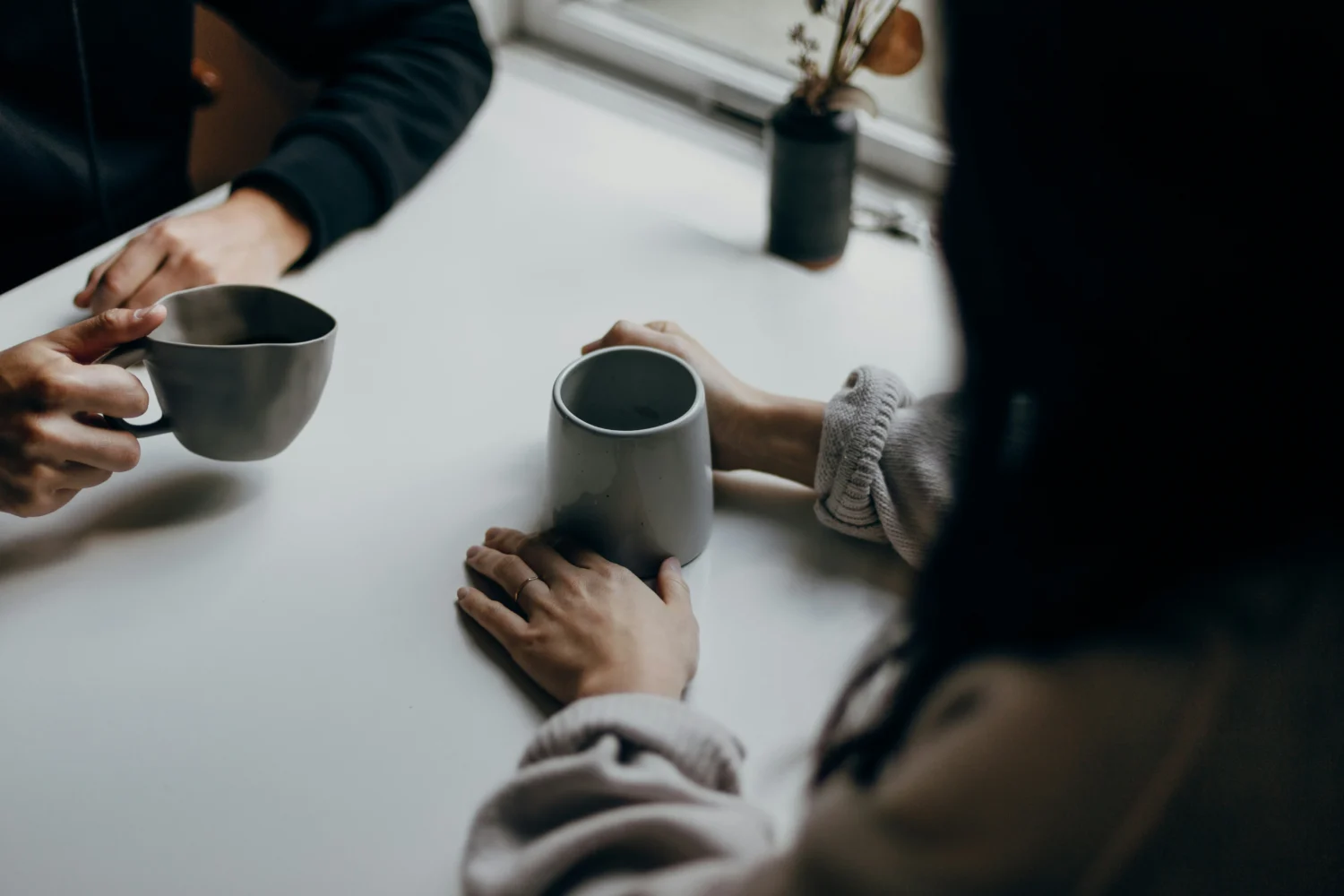 Two people leaning in towards each other holding tightly to a coffee cup