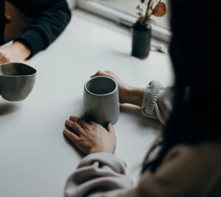 Two people leaning in towards each other holding tightly to a coffee cup