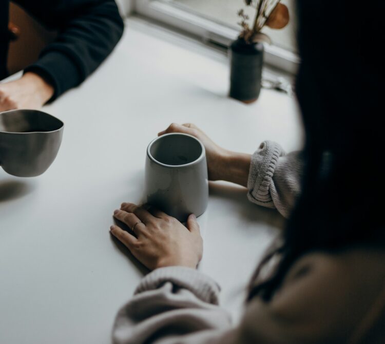 Two pairs of hands holding coffee mugs