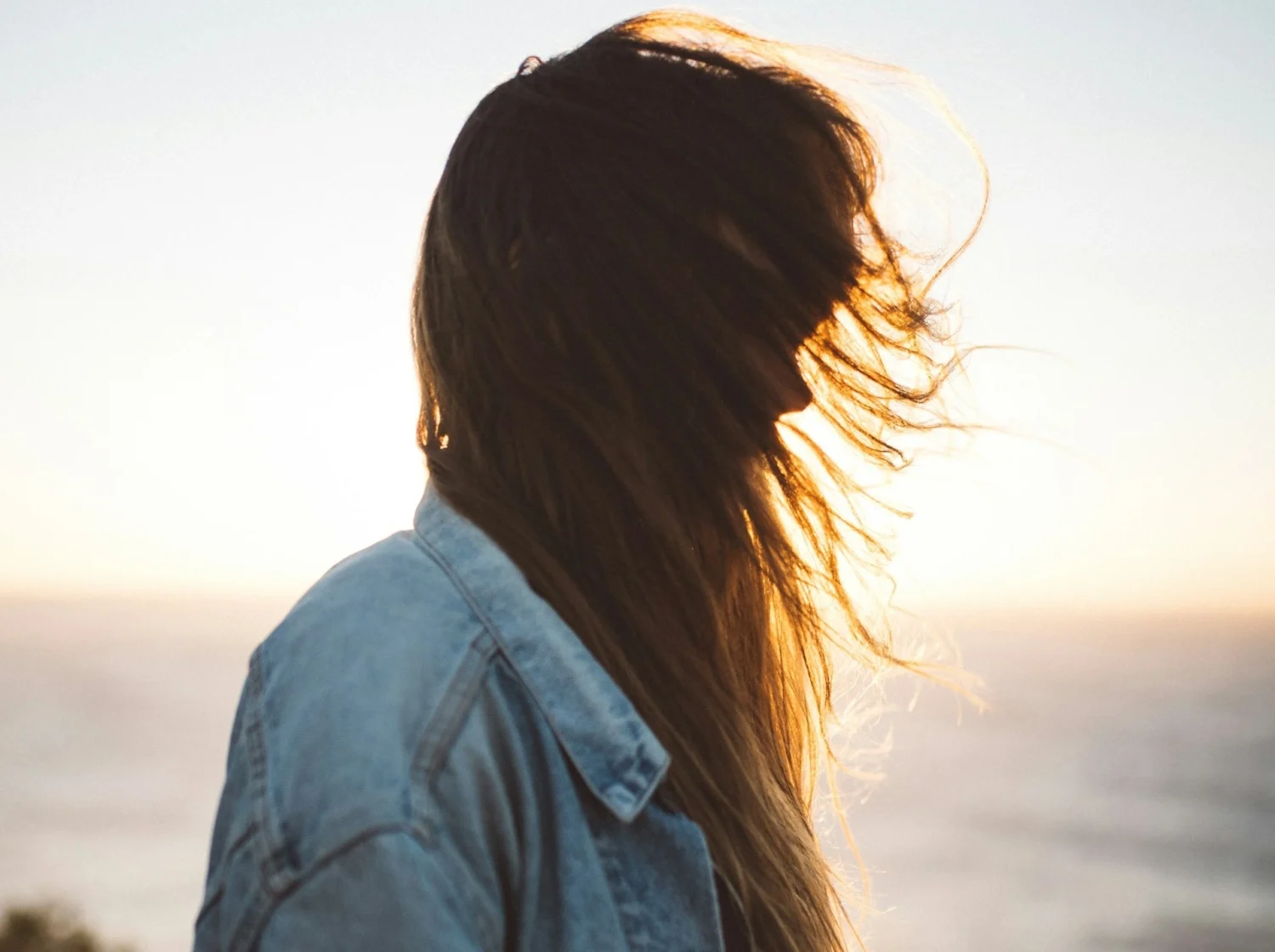A woman standing side on with her hair blowing across her face