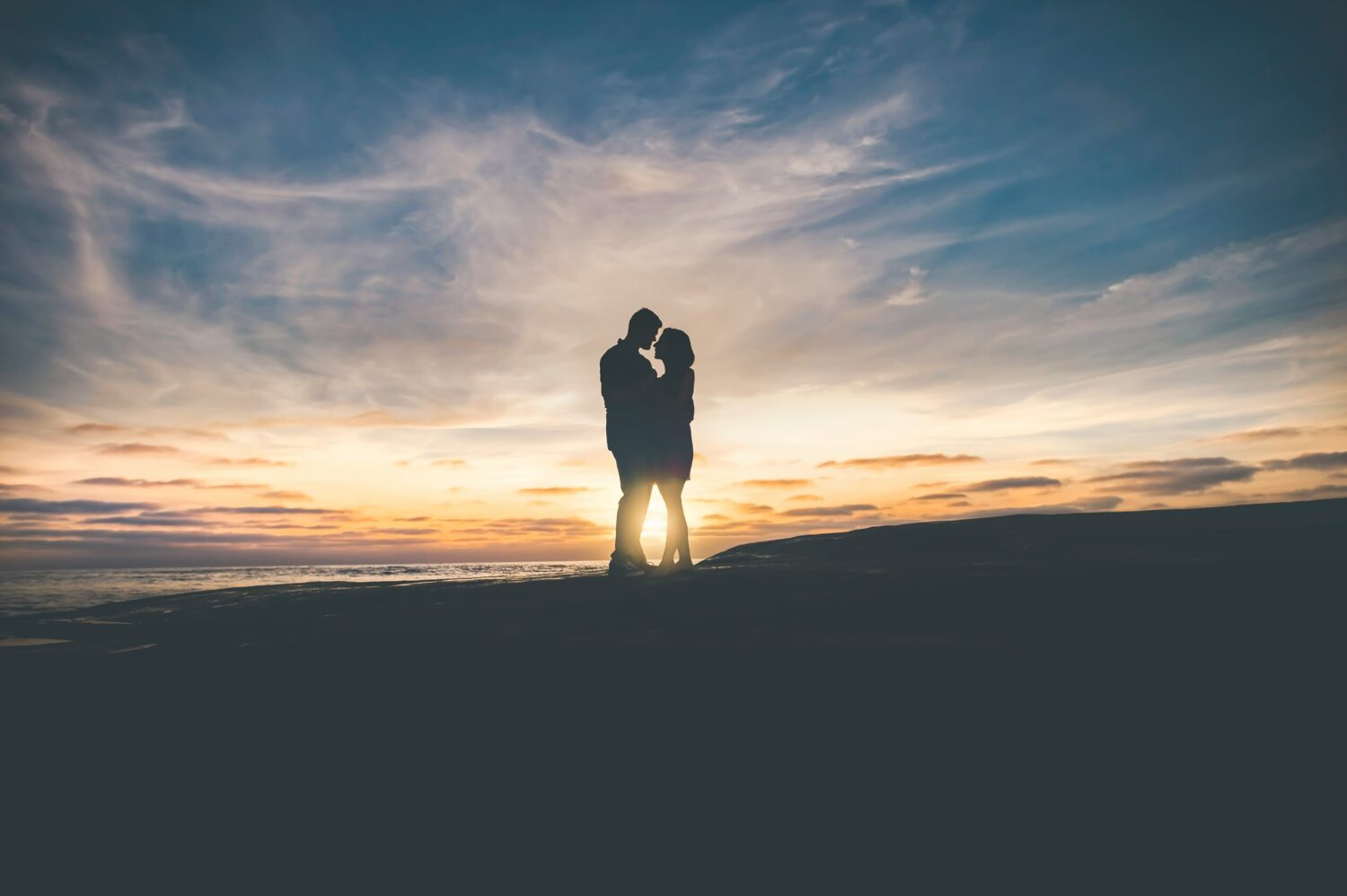 Couple in the distance as a silhouette in sunset talking very closely