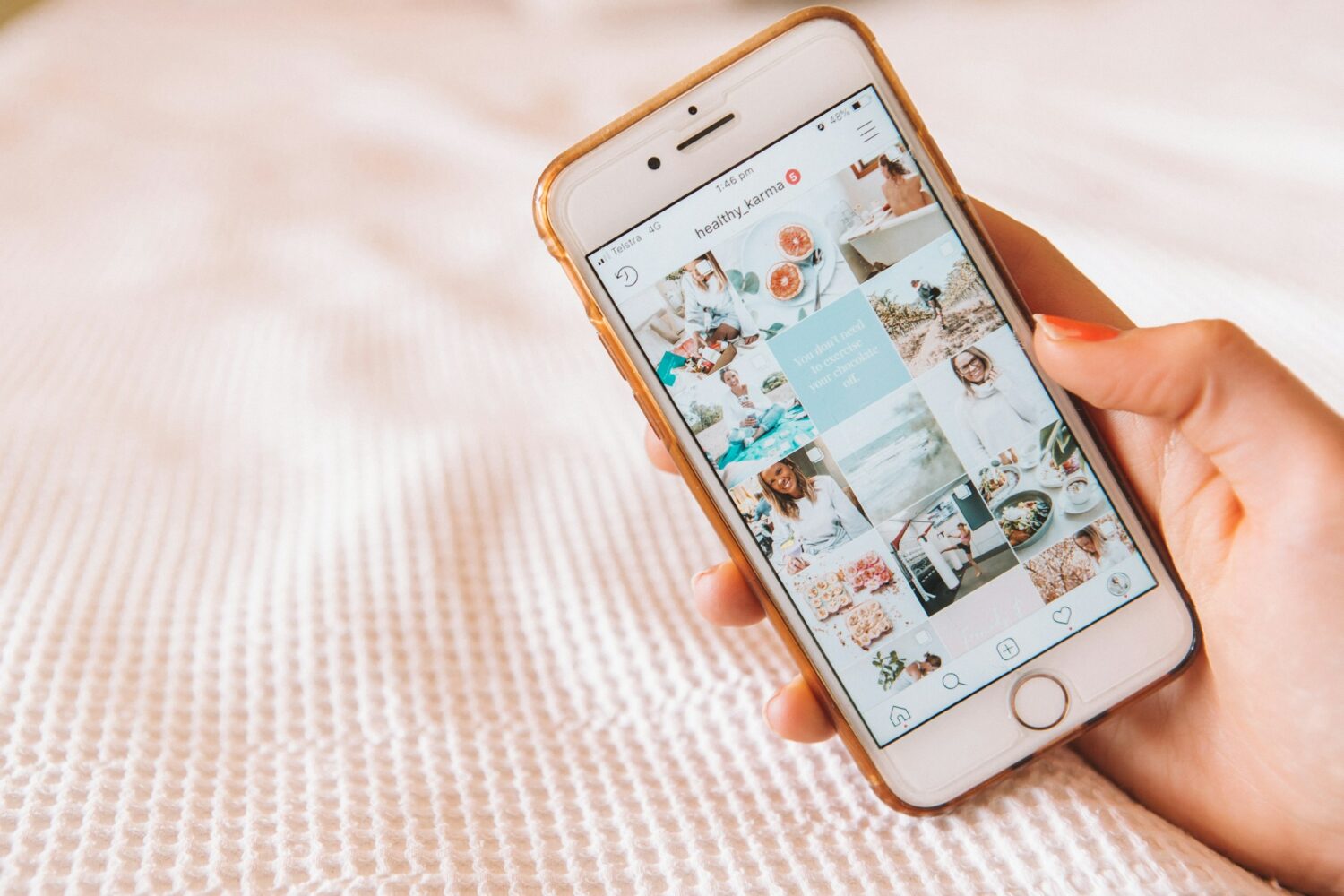 A hand holding an iPhone showing a wellness-based instagram page