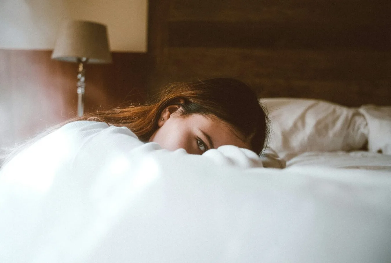 Woman leaning on bed with part of her face covered