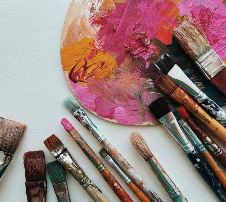 A collection of paintbrushes on a pink palette.