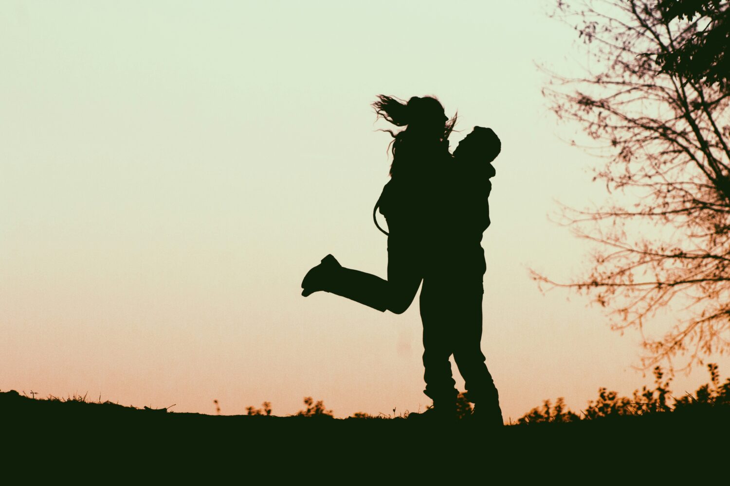 shadow of female jumping onto partner with legs in air and partner catching her