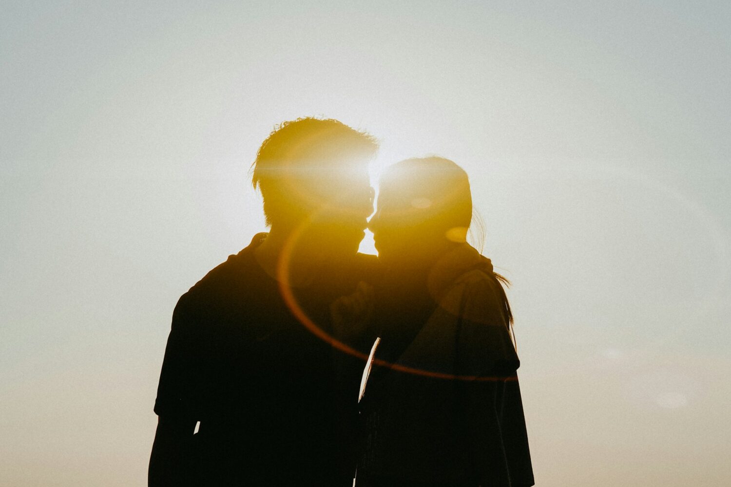 Two people silhouetted by the sun embracing