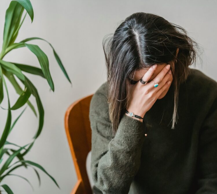 Woman holding head in hand.