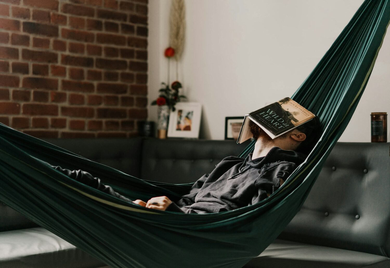 A man sleeping in a hammock with a book over his face