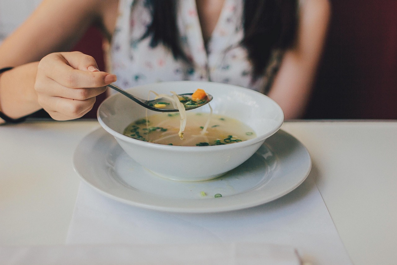A person eating a bowl of chicken noodle soup