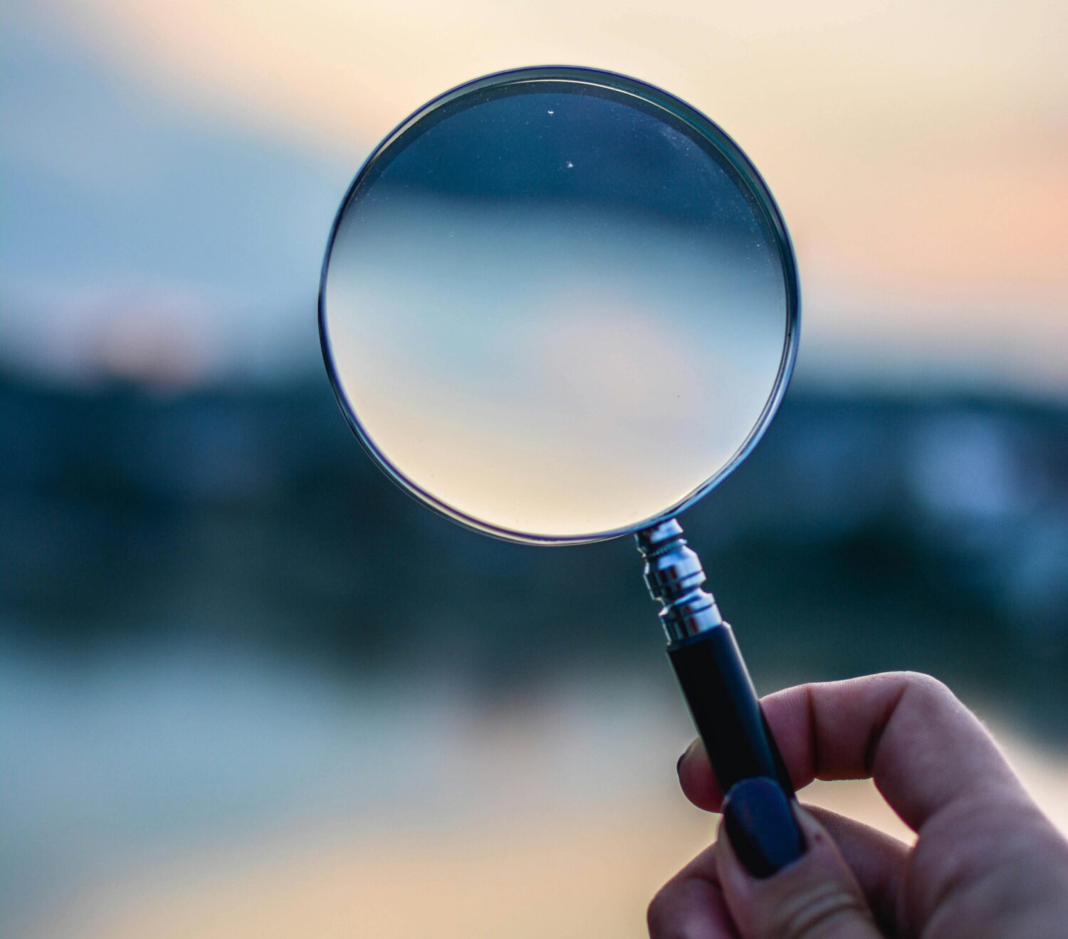 Hand holding magnifying glass.