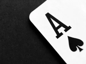 Close-up of an ace of spades playing card on a black surface.