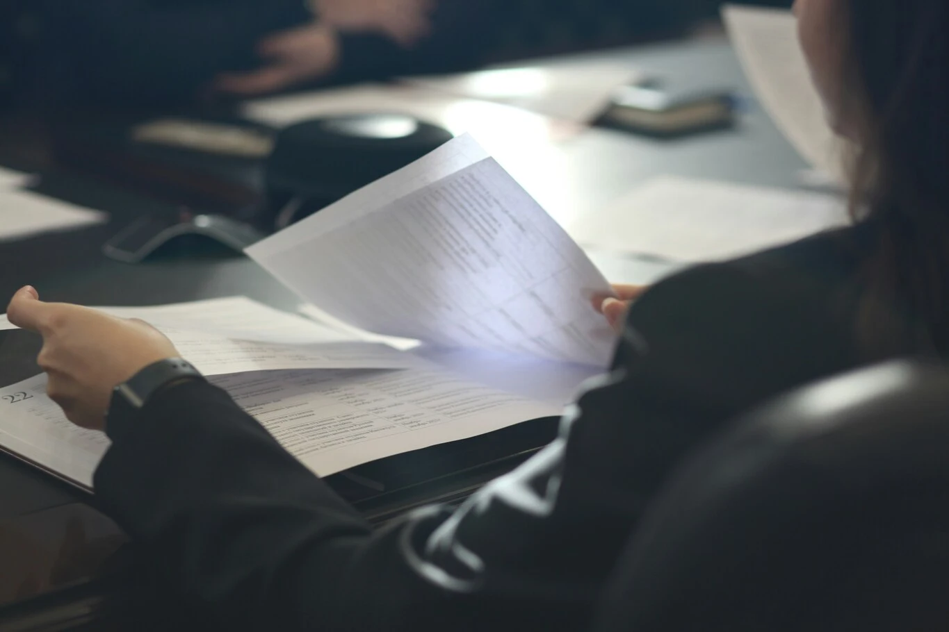 Woman holding a document and reading papers at a desk.