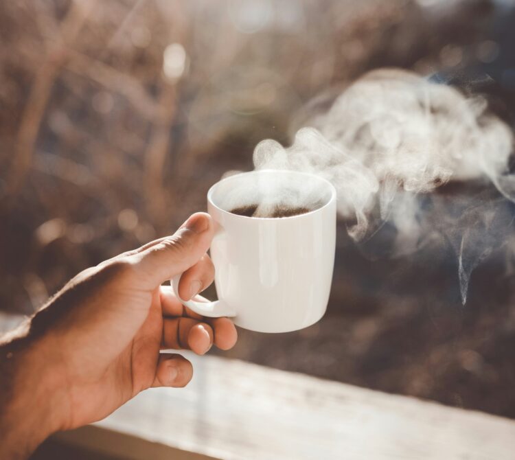Person holding coffee cup with steam