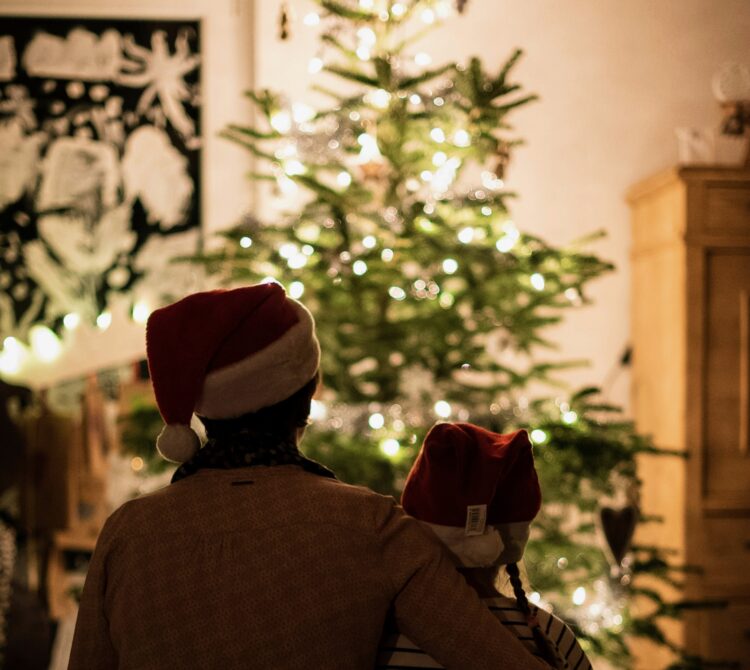 Two people hugging and looking at a Christmas Tree