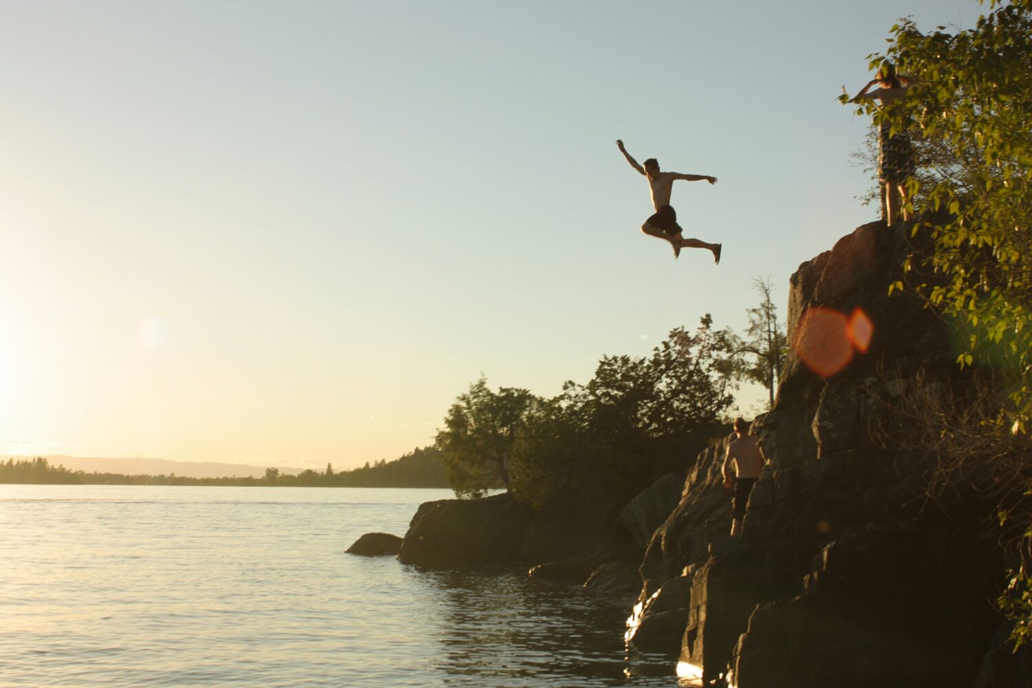 A person bravely jumping into a swimming hole a high rock