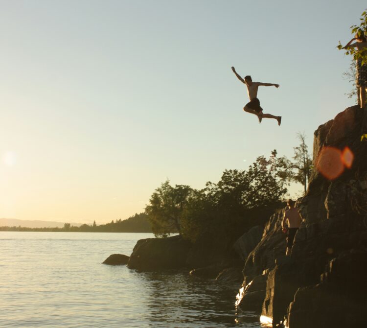 A person bravely jumping into a swimming hole a high rock