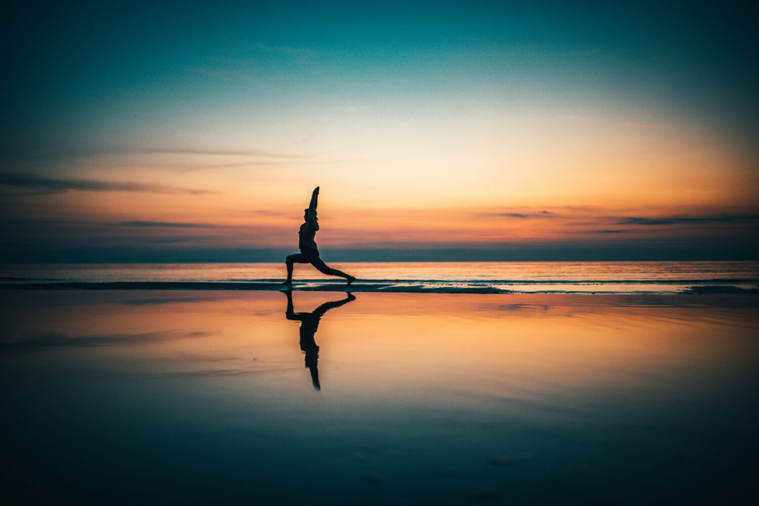 Women doing yoga on the beach in sunset