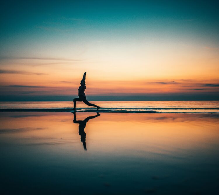 Women doing yoga on the beach in sunset