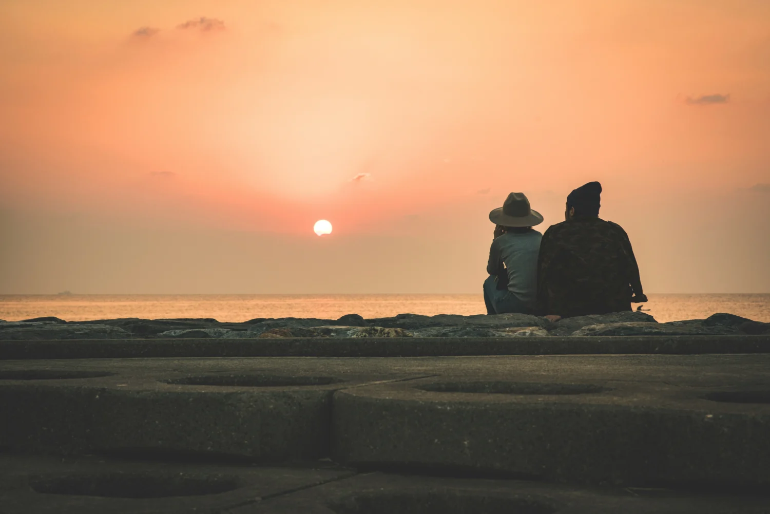 Two people sitting down looking at the sunset