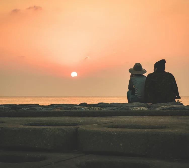 Two people sitting down looking at the sunset