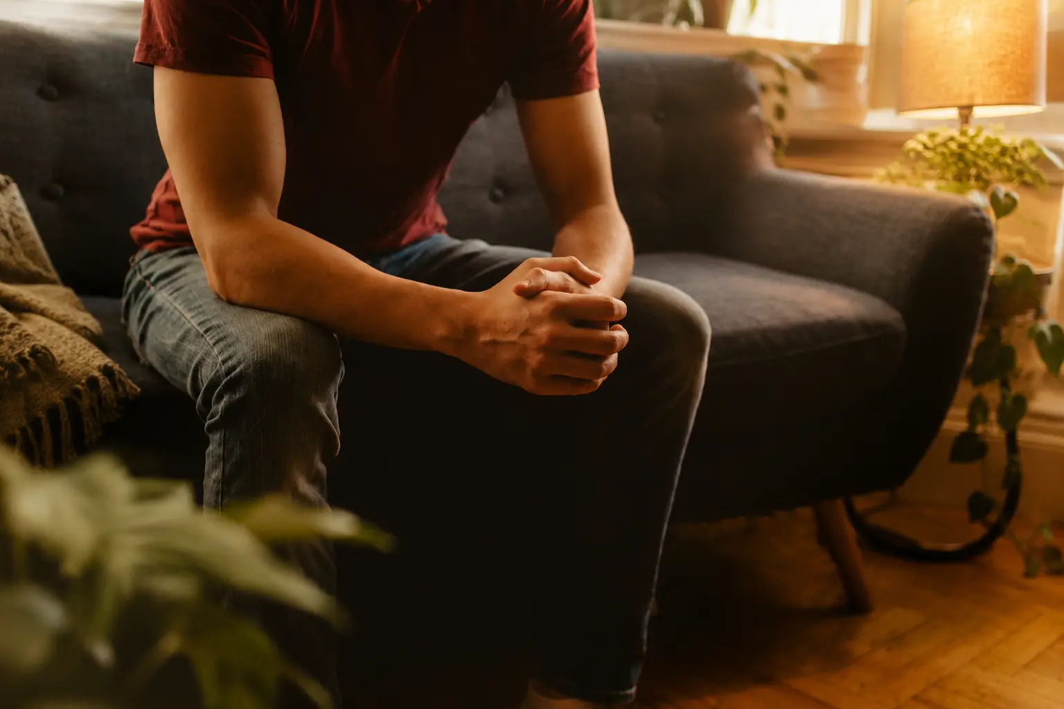 Man sitting in therapy room on a couch with warm lighting
