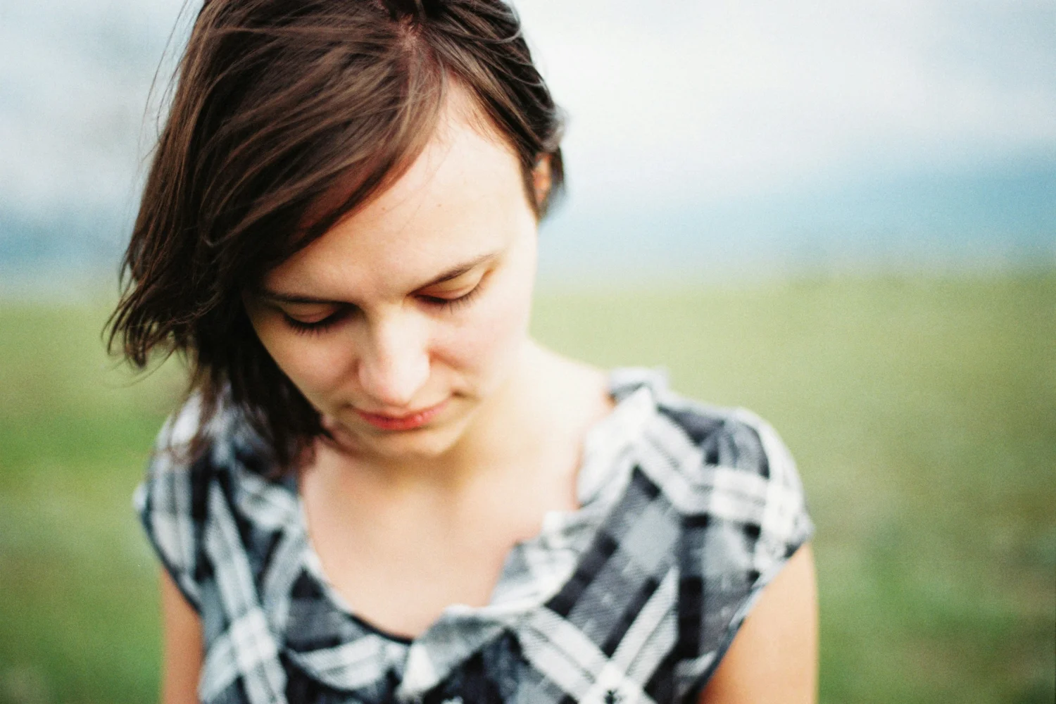 Women standing in grass field looking downwards with sad expression